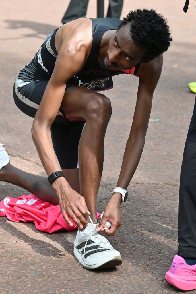 Elite runner lacing shoes on ground after finishing TCS London Marathon 2026
