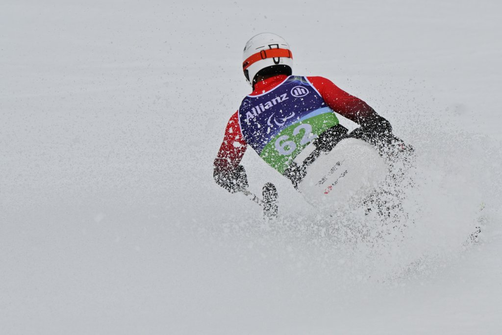 Sit-ski racer spraying snow at finish line at Milano Cortina 2026 Winter Paralympics