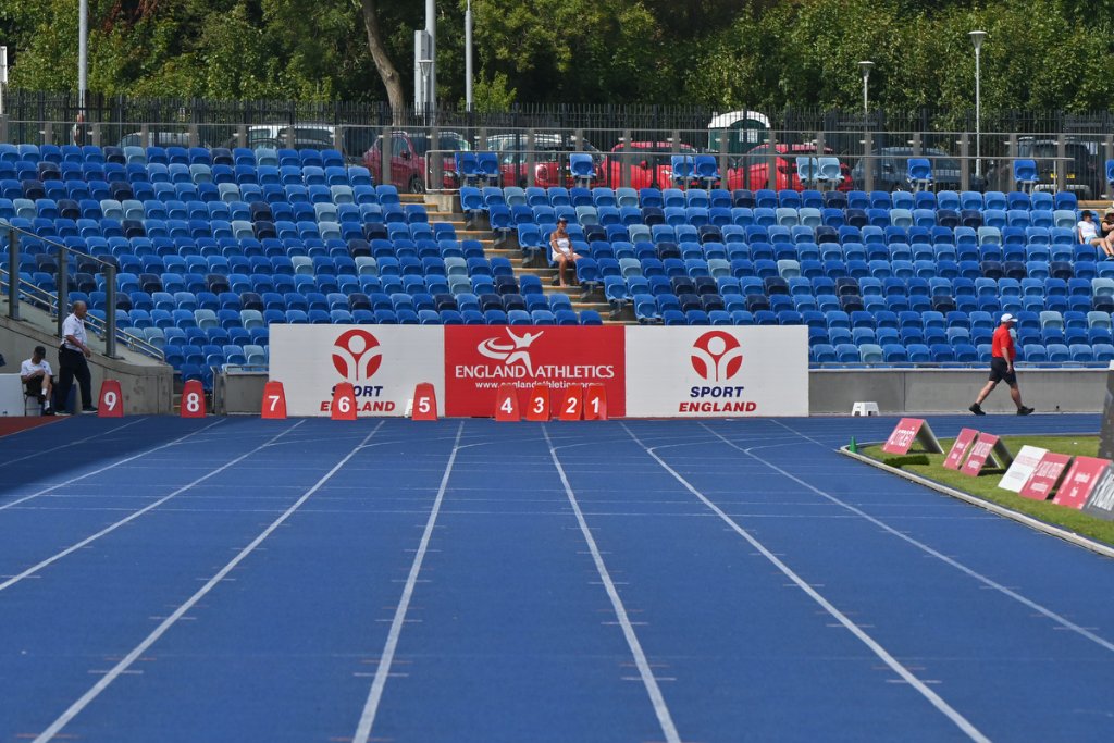 Visually impaired athlete in red with guide runner on the track