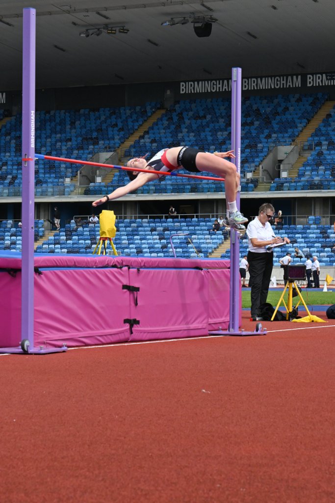 High jumper in black clearing the red and blue bar at Birmingham