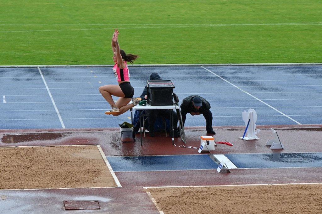 Para athlete performing long jump in the rain