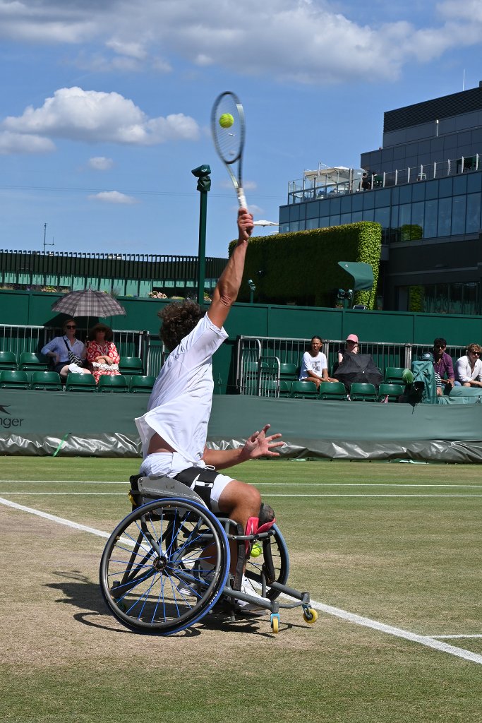 Wheelchair tennis player serving powerfully at Wimbledon