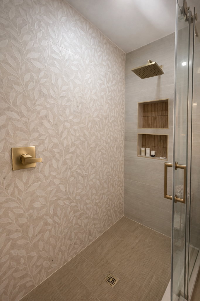 Magnolia Suite walk-in shower with botanical leaf tile, gold rainfall showerhead, glass door, and built-in shelving at Laurel Haven Estate