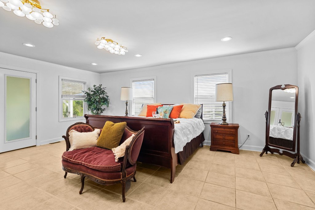 Palmetto Suite spacious king bedroom with mahogany sleigh bed, burgundy velvet chaise, freestanding mirror, and French doors at Laurel Haven Estate