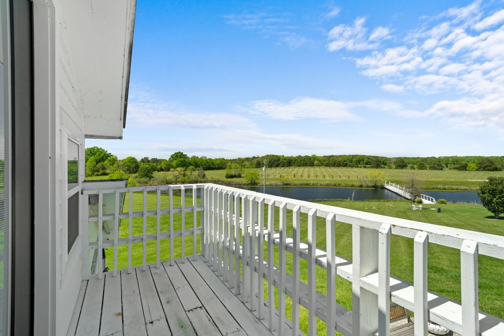 Vineyard deck overlooking vineyard rows, pond, and bridge at Laurel Haven Estate