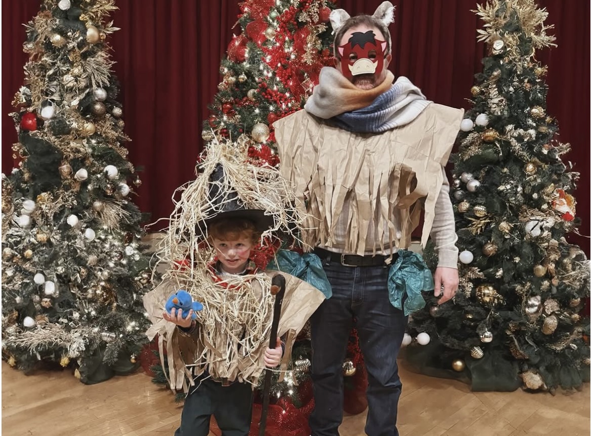 A young scarecrow in a straw hat beside a masked contestant in a fringed tunic