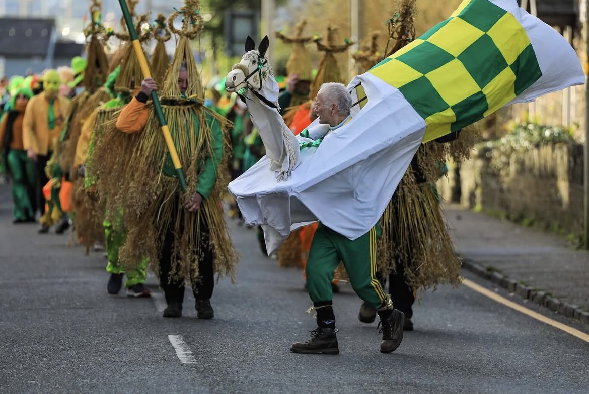 A wren day procession with a straw hobby horse and checkered flag