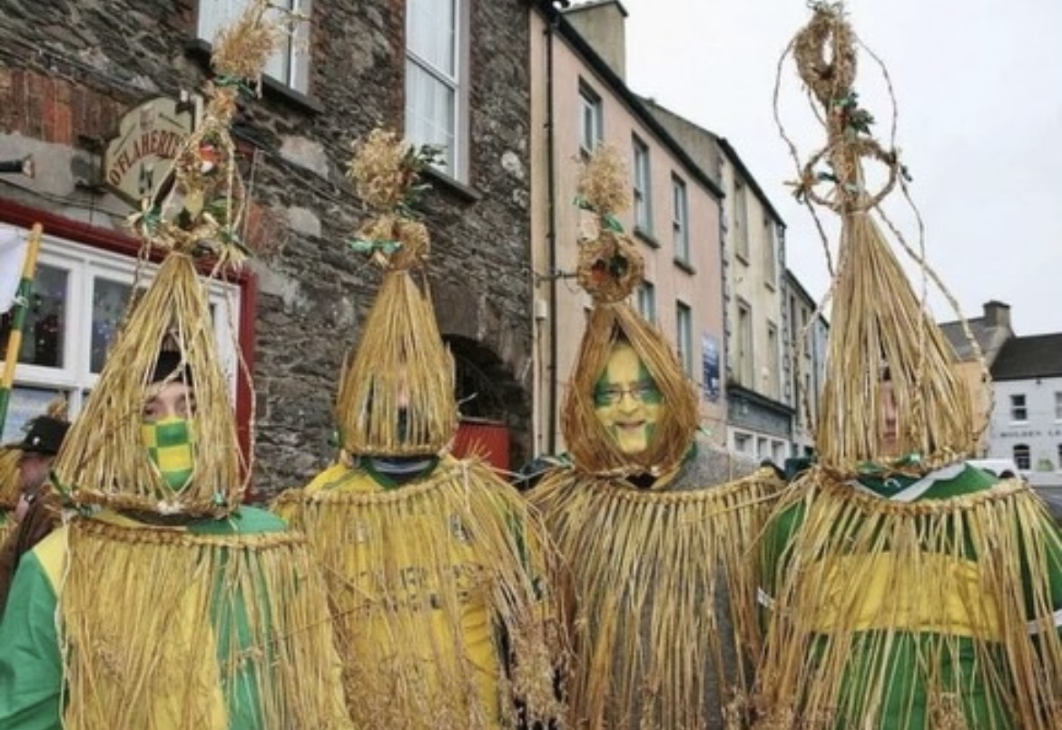 Four wren boys in straw costumes outside a pub
