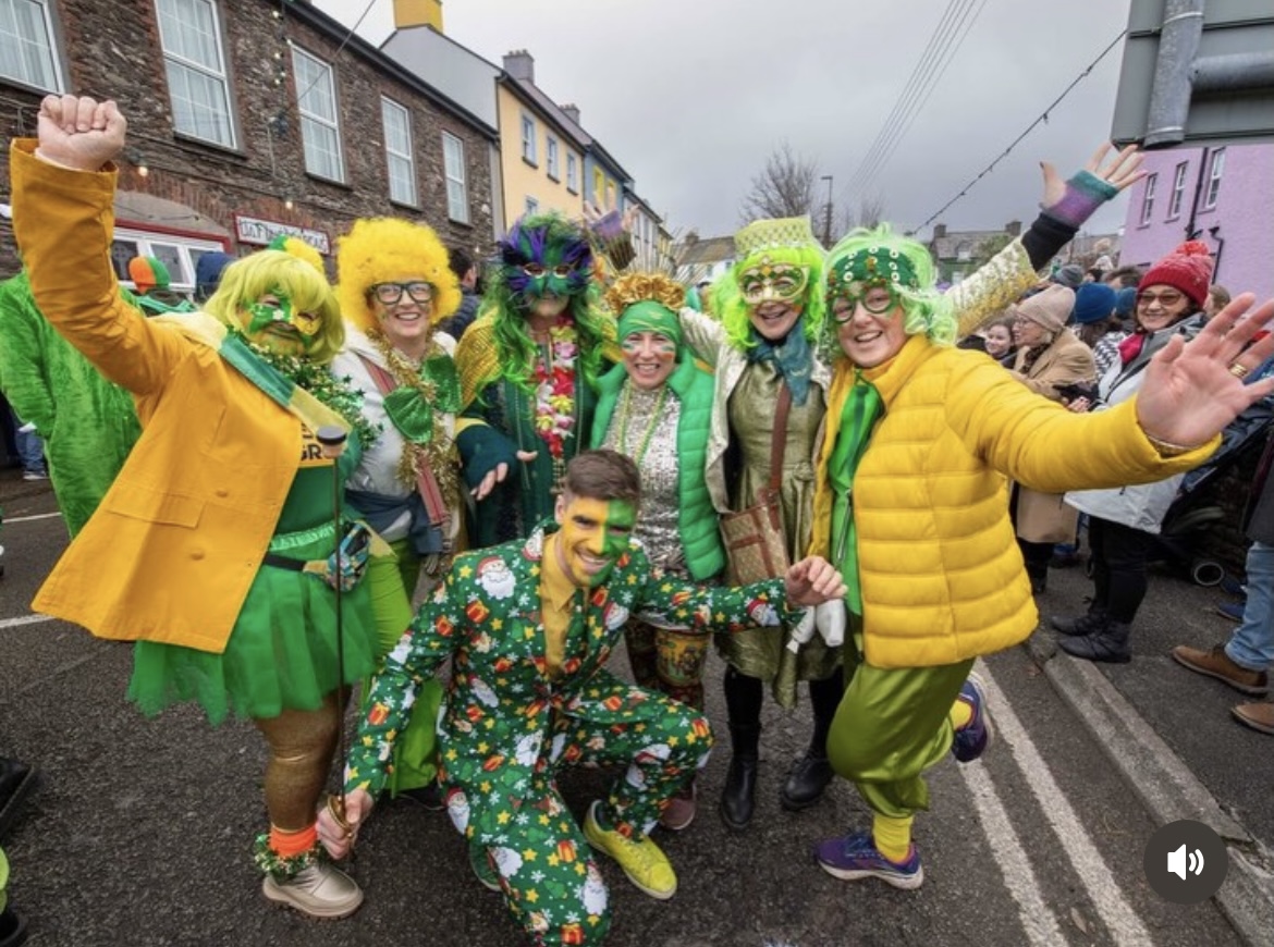 A group in green and gold folk costumes celebrating on the street