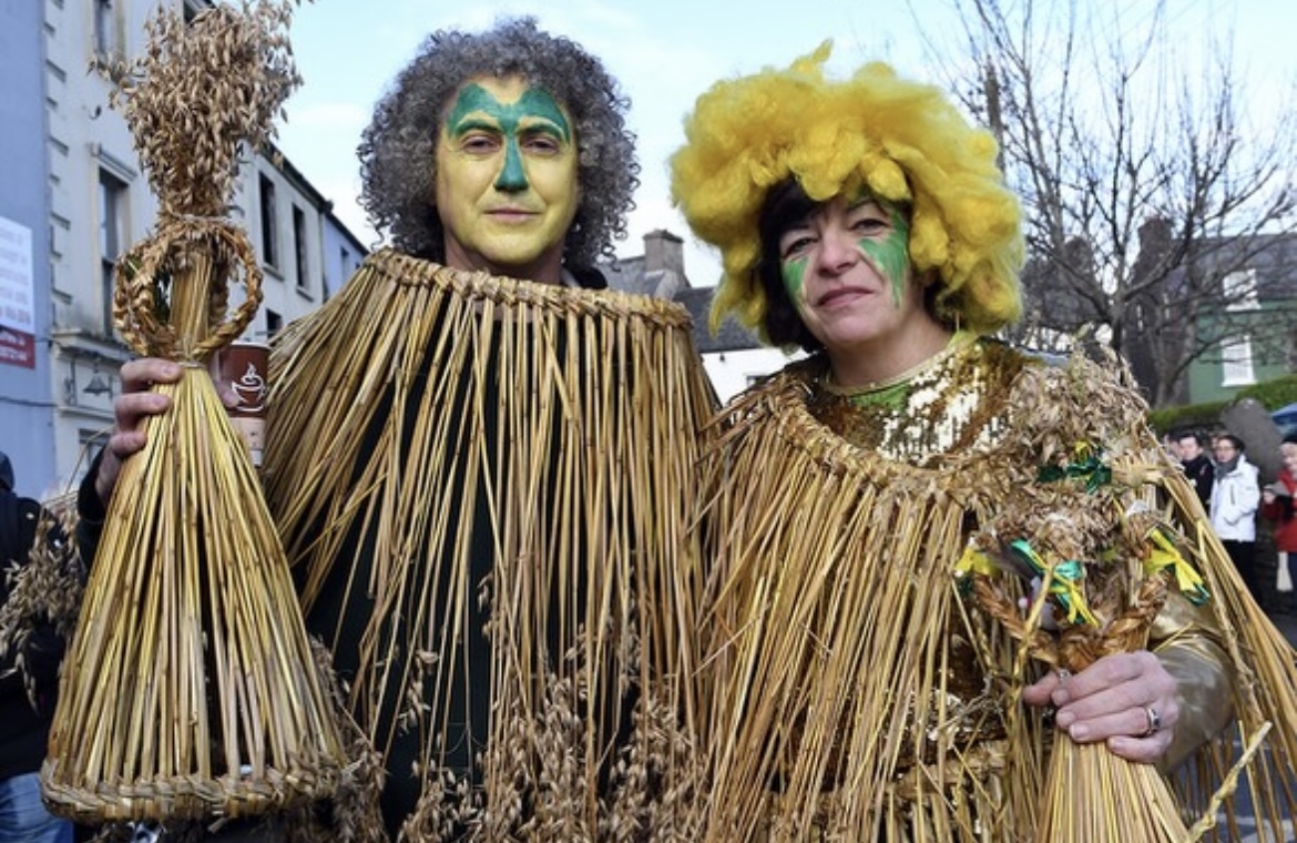 Two wren boys in straw costumes with green and yellow face paint