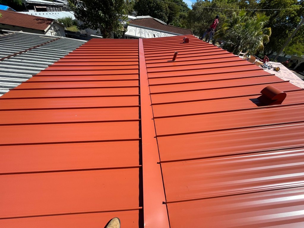 Completed red standing seam metal roof replacement with ridge cap and vents in South Florida
