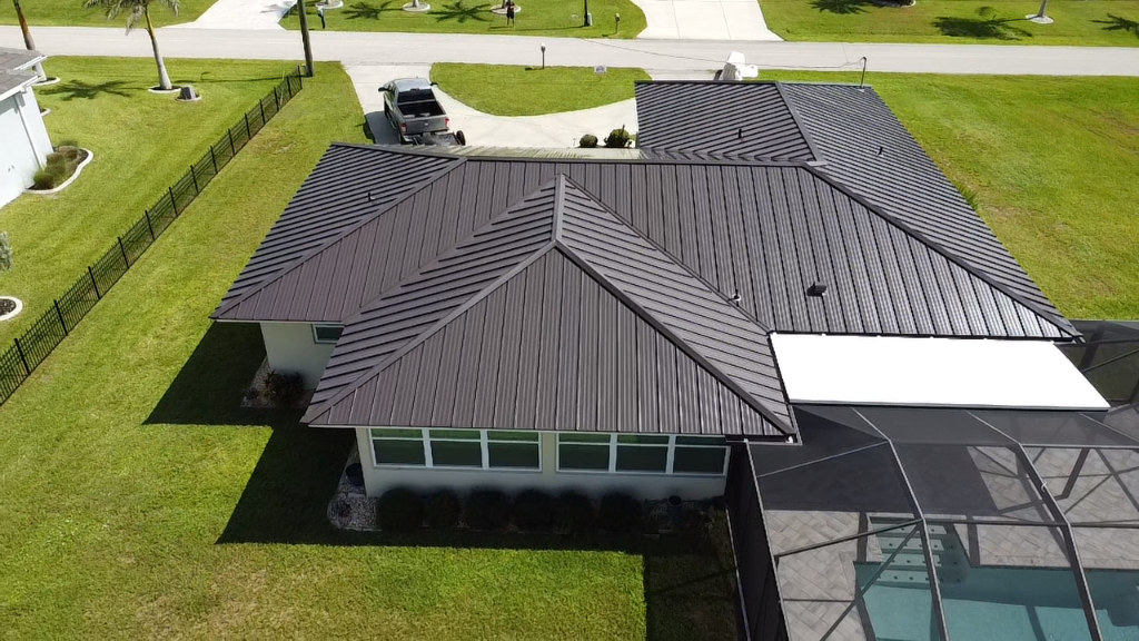 Aerial view of bronze standing seam metal roof installation with pool enclosure in South Florida