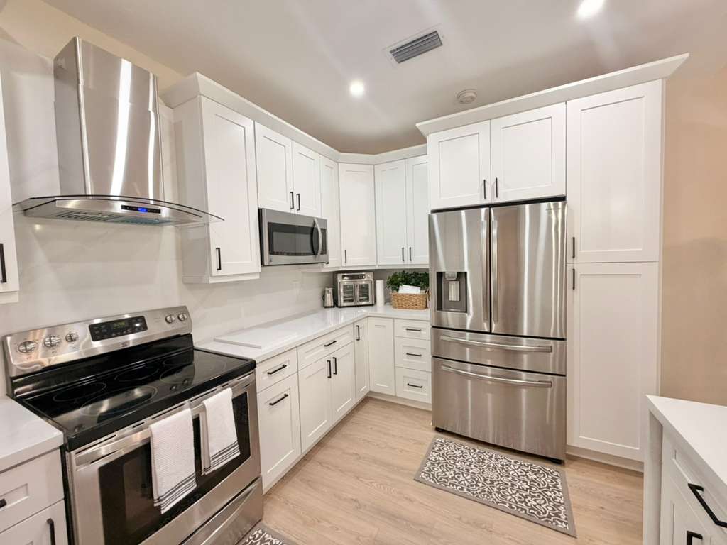 Modern kitchen remodel with white Shaker cabinets, stainless steel appliances, and light wood-look flooring in South Florida