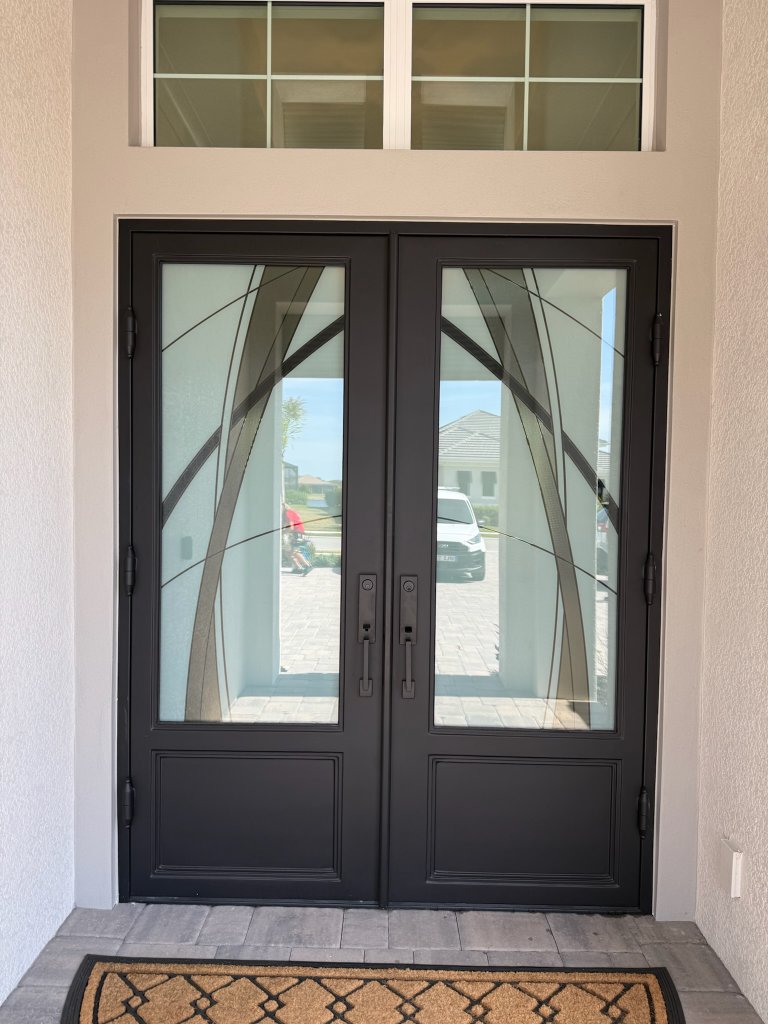 Curved dark accents on entry doors beneath a clear transom