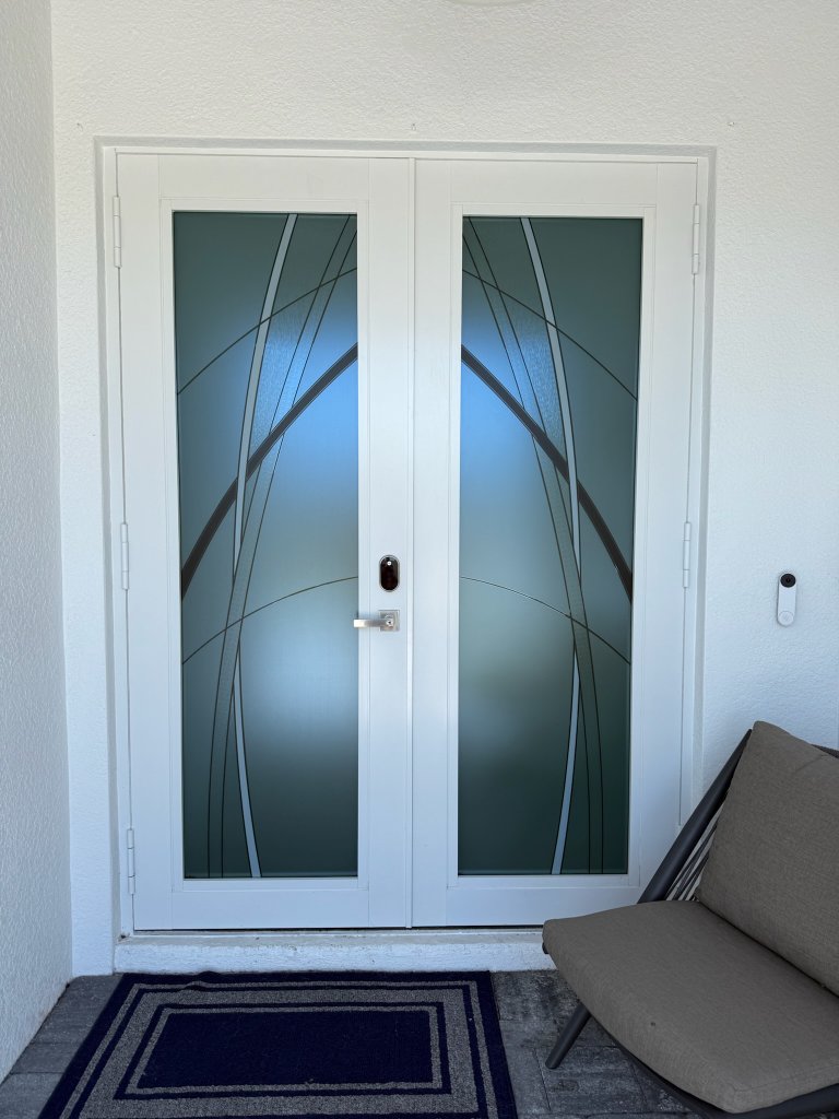 Dark curved accents on white-framed double entry doors