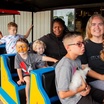 Carnival rides and inflatables at a large outdoor event by Life Unlimited