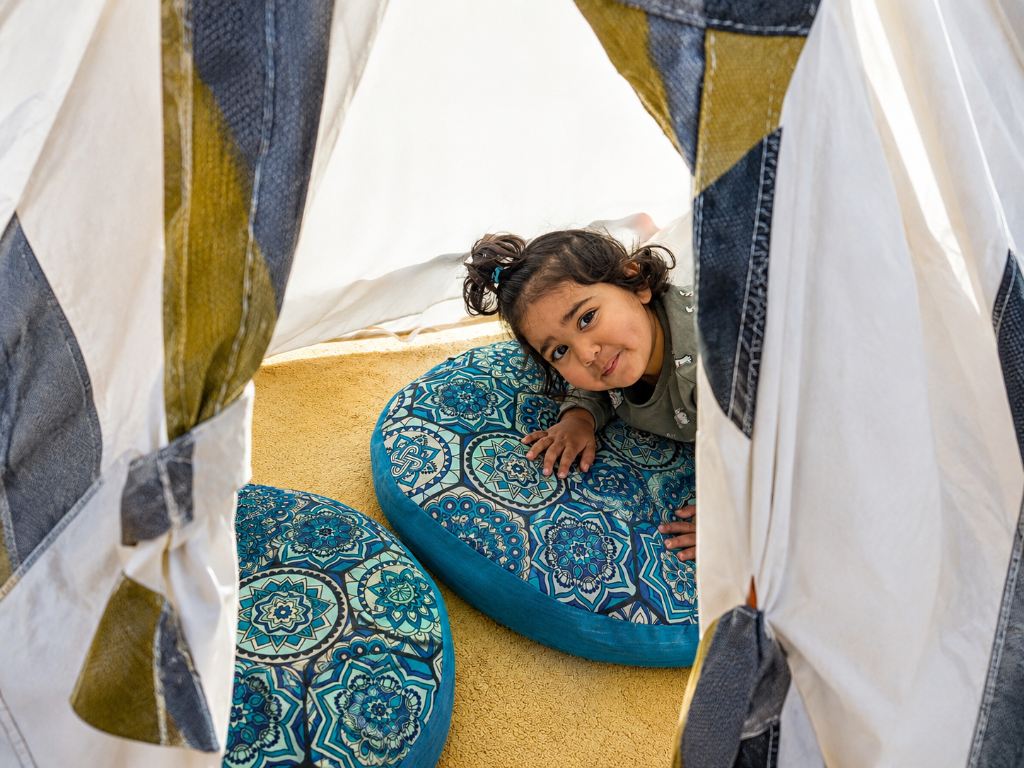 Child peering out from a teepee tent
