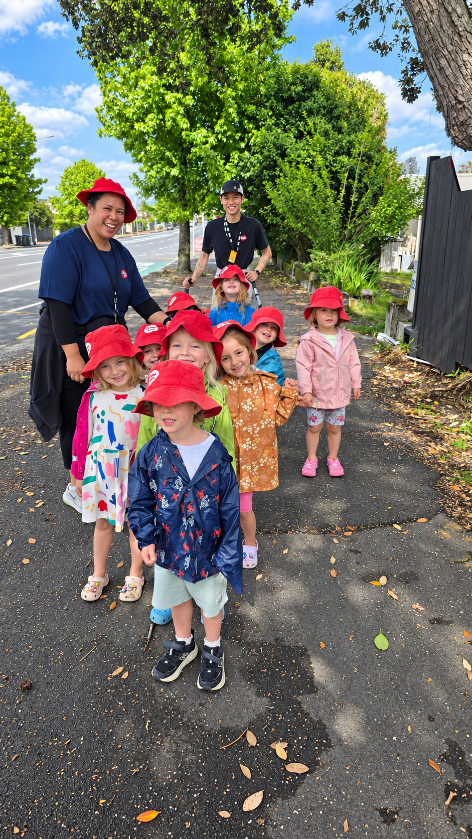 Teachers and children in red hats out on a walk