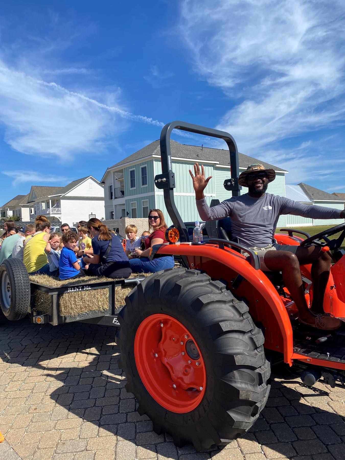 Evergreen Tractor Kubota tractor pulling a trailer full of children on a community hayride through a neighborhood