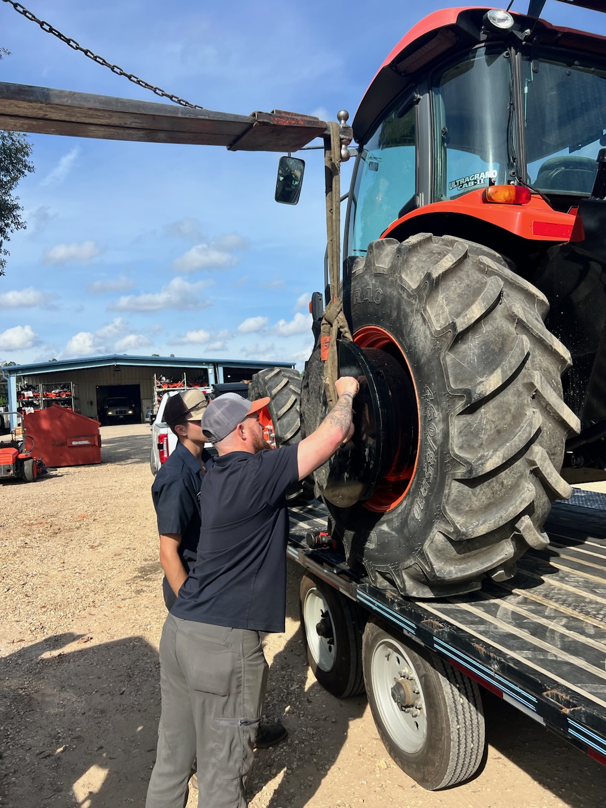 Evergreen Tractor service technicians installing a new wheel assembly on a Kubota tractor