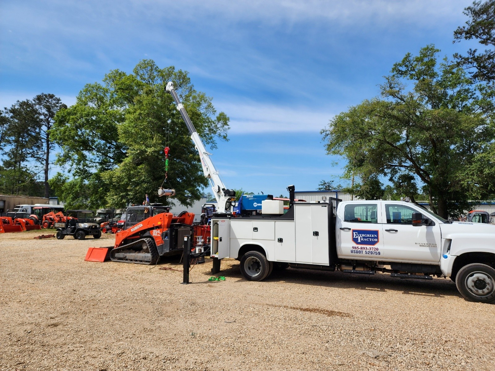Evergreen Tractor mobile service truck using a crane to service an orange Kubota SVL95-2s compact track loader