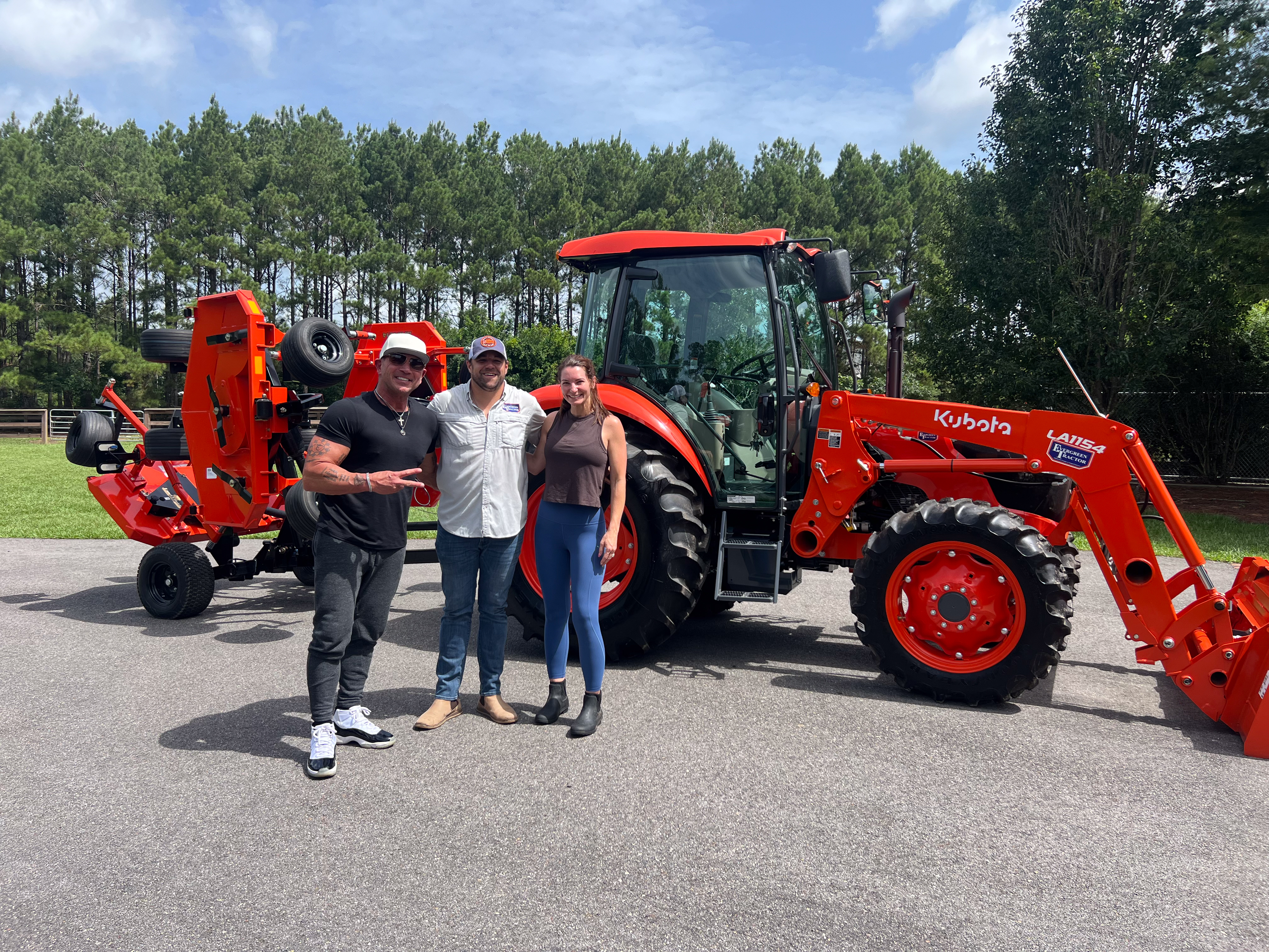 Evergreen Tractor customers posing with their Kubota tractor, LA1154 loader, and rotary cutter