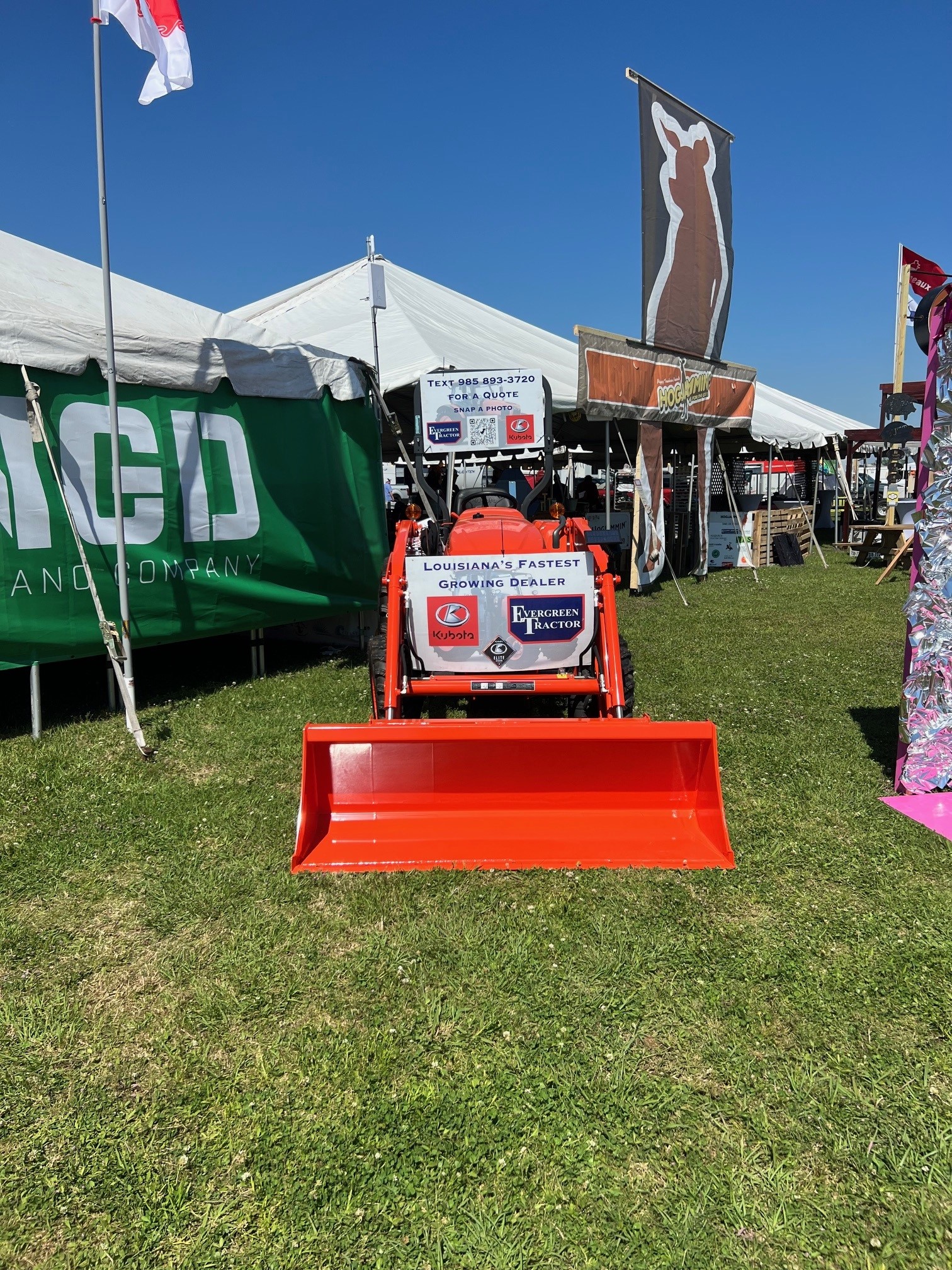Orange Kubota tractor with Evergreen Tractor signage on display at a local community event