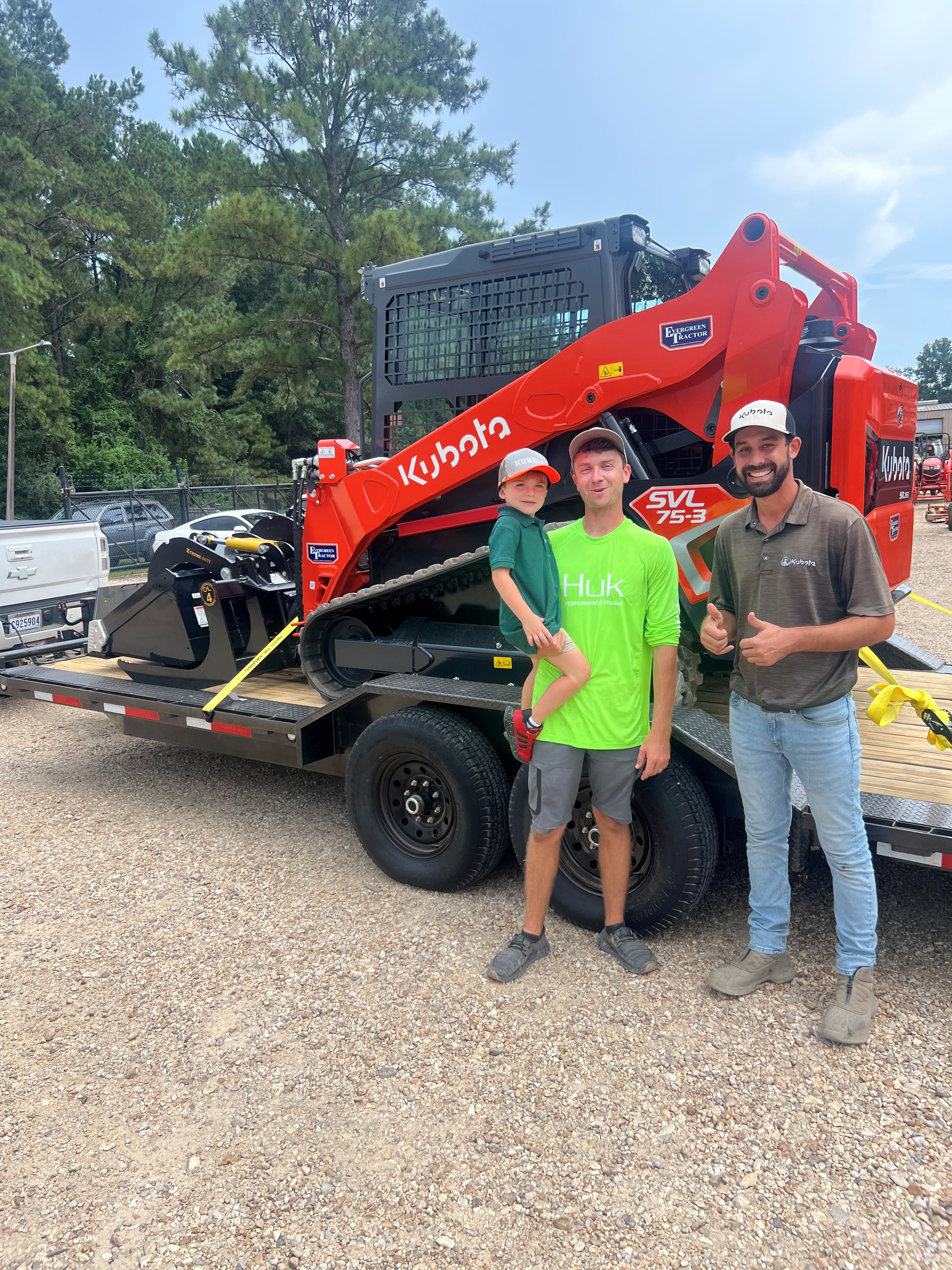 Evergreen Tractor customer pickup — a family posing with their new Kubota SVL75-3 loaded on a trailer