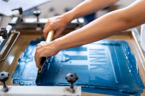 Close-up of a person screen printing a shirt at Next Gen Prints