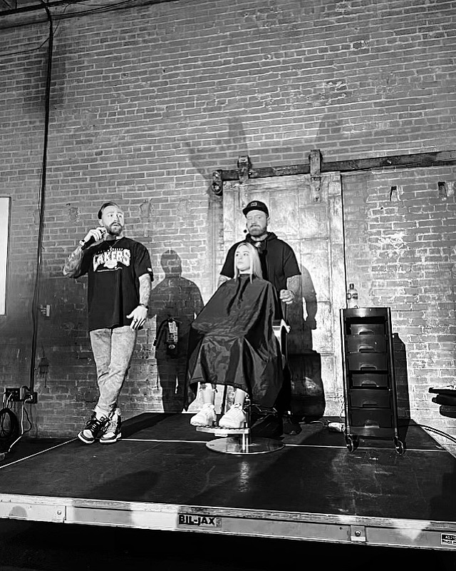 Cody Warren speaking on stage during a live hair and education presentation