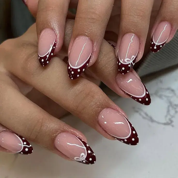 Dark red French almond nails with white polka dots and bow