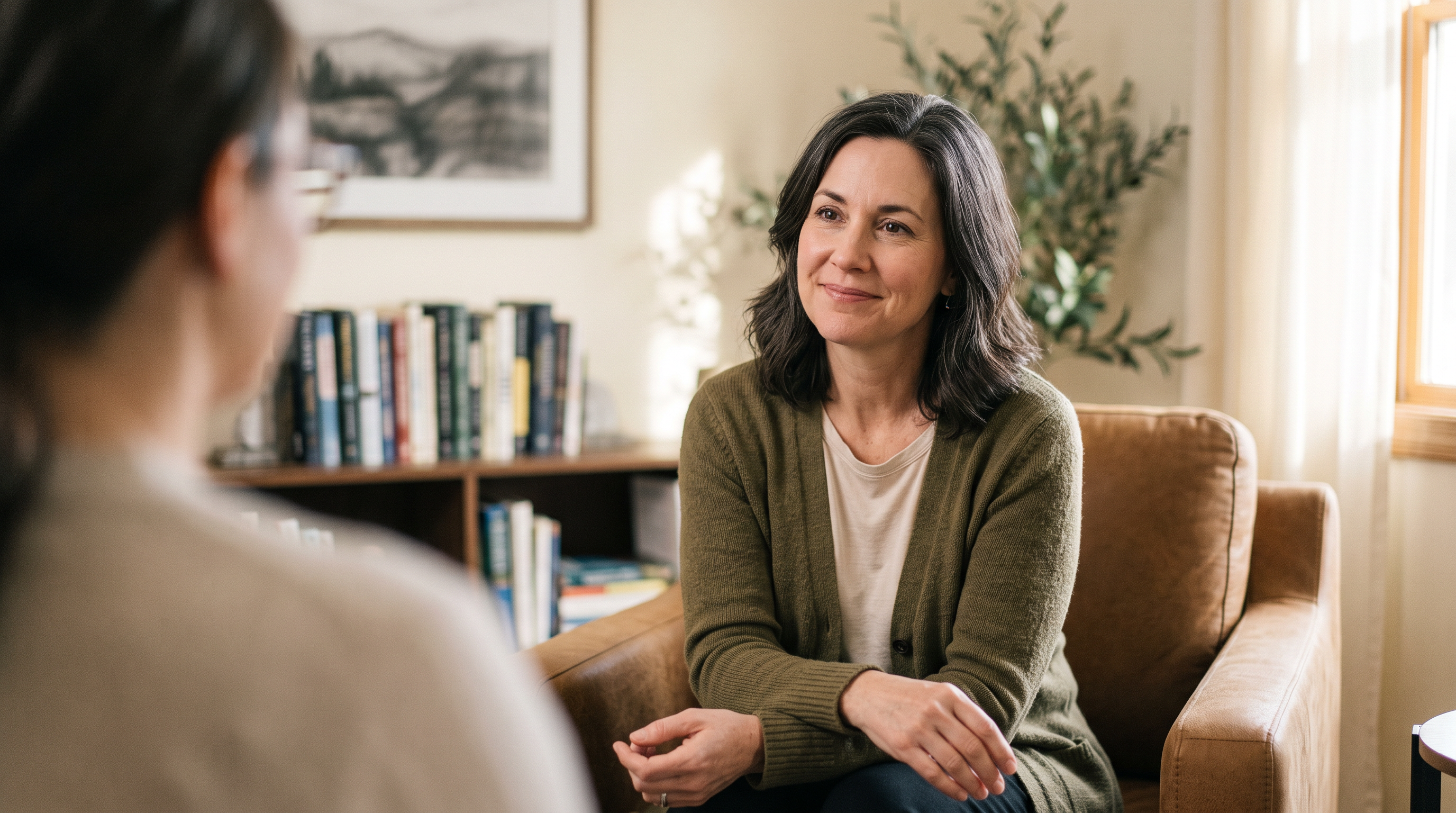 Trauma recovery coach listening attentively to a client in a warm, welcoming office