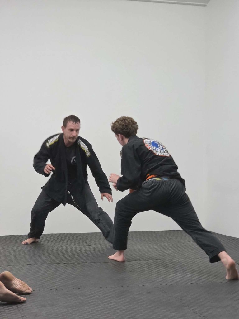 Two students sparring in low stances on the mats