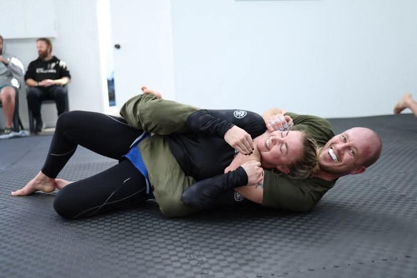 Two students practicing a grappling drill on the mats
