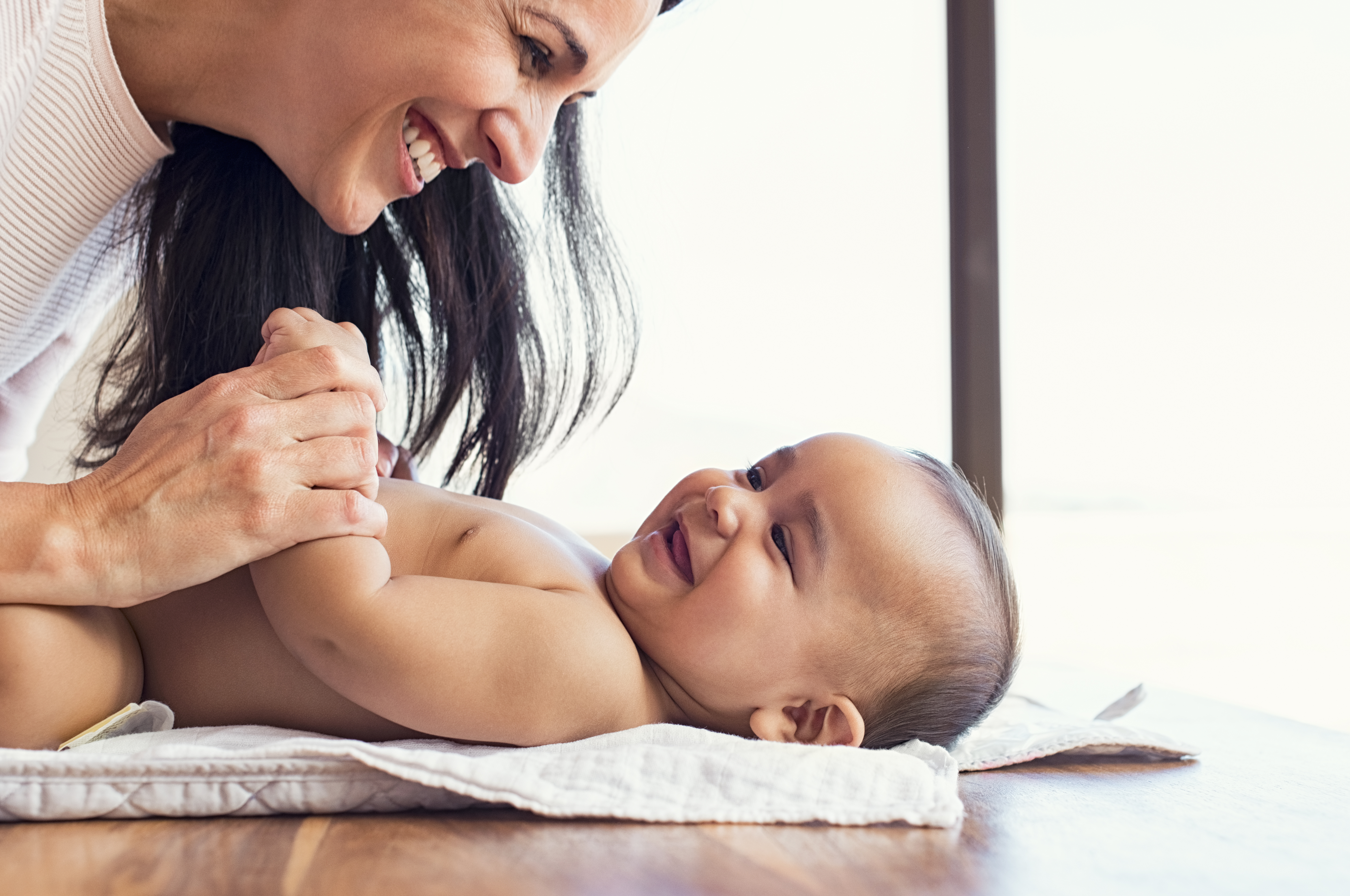 Mother playing with a smiling baby on a soft mat