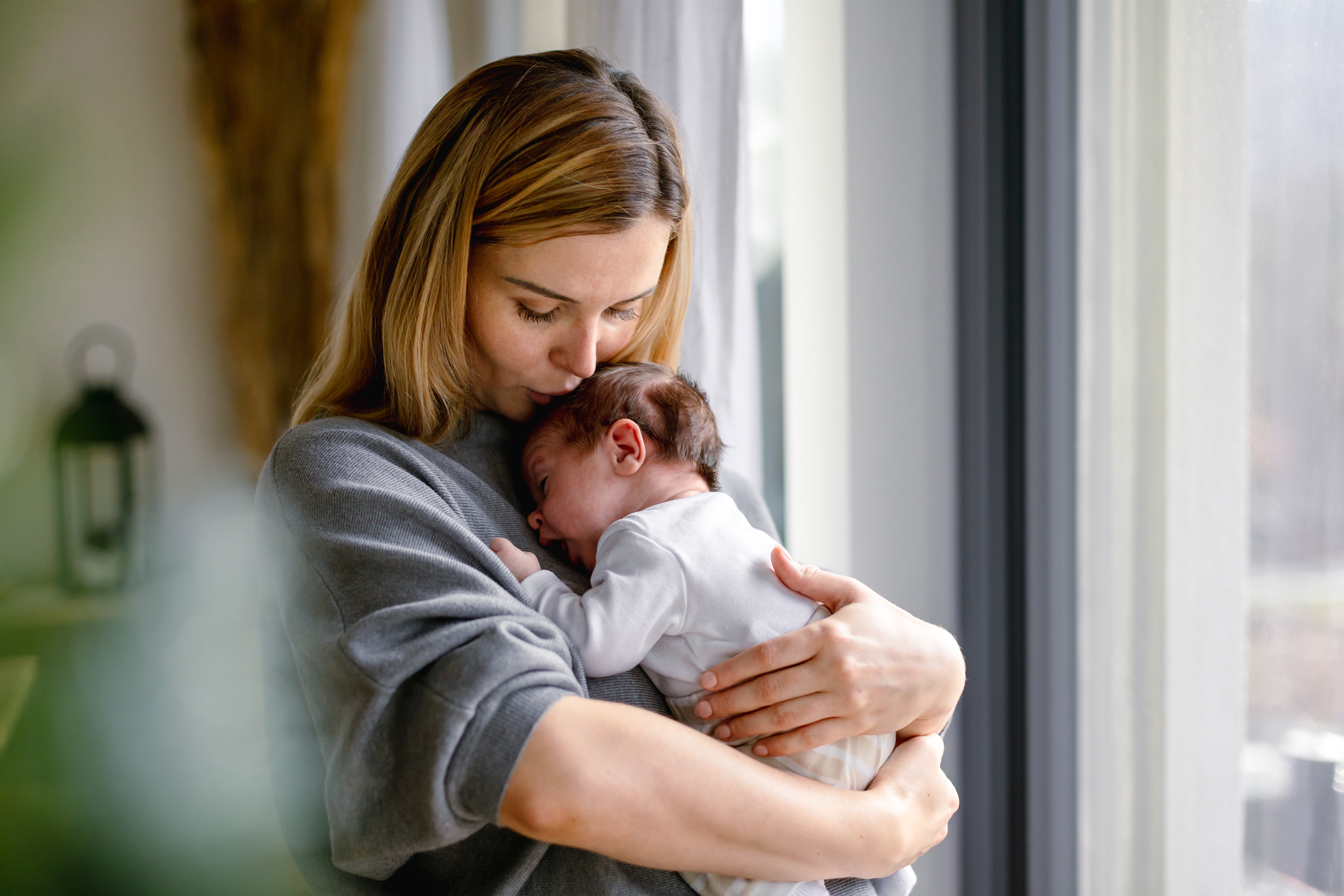 Mother kissing the head of her newborn baby