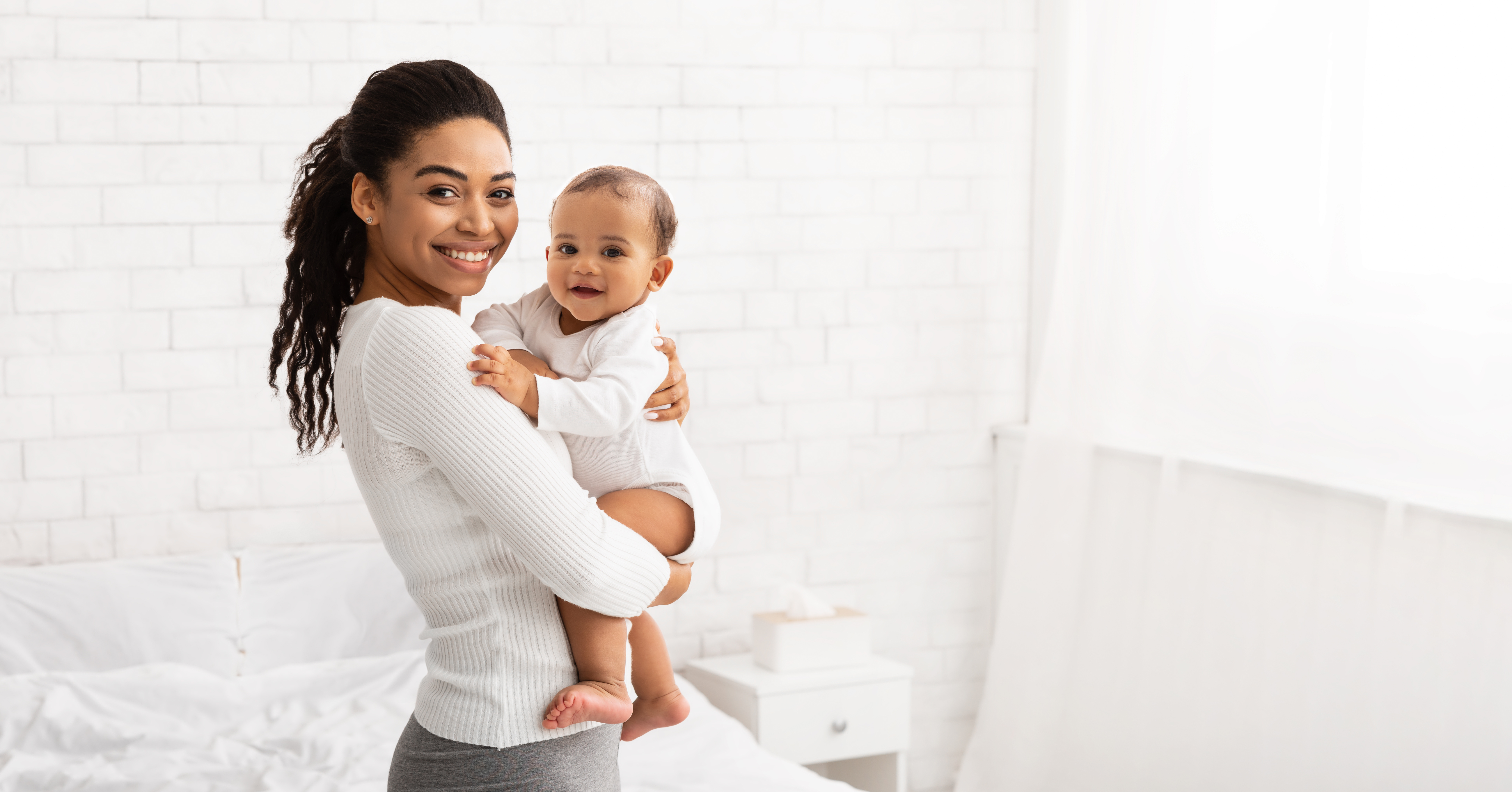 Mother smiling while holding her baby at home