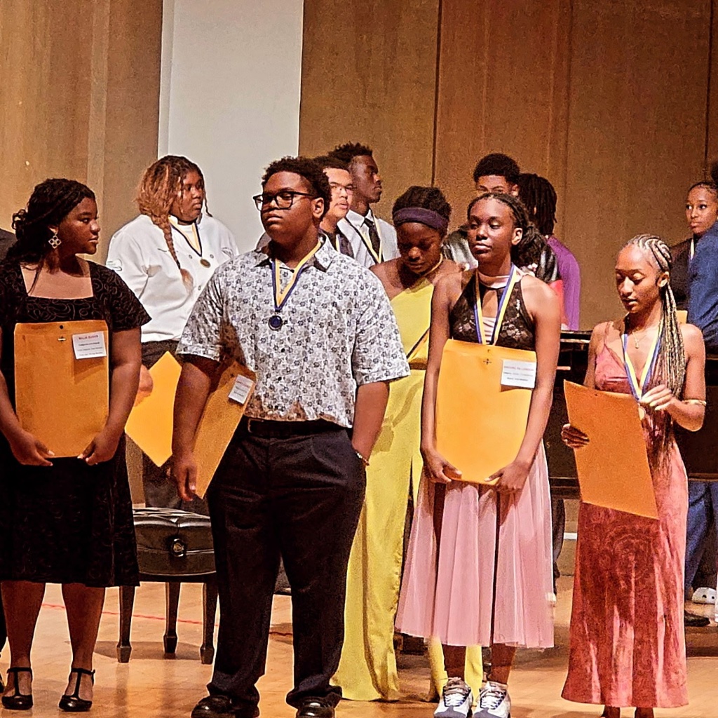 Students on stage holding award certificates