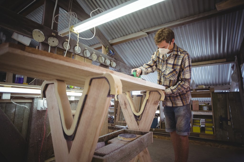 Craftsman sanding a large wooden board in a workshop