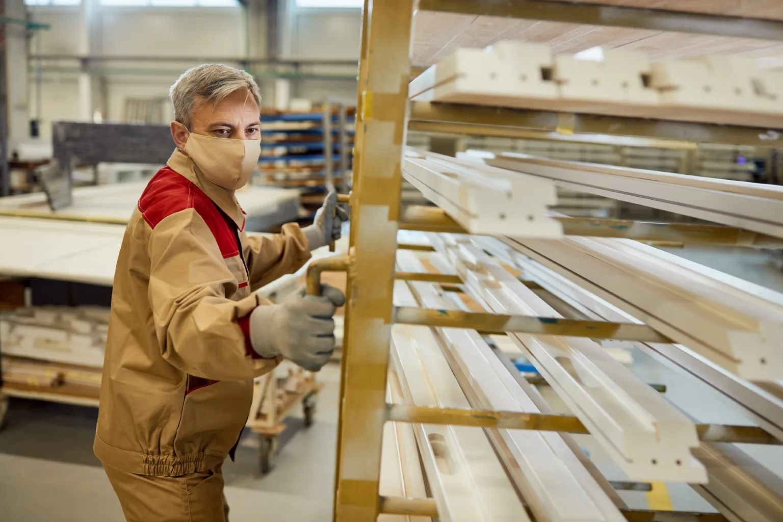 Worker moving a rolling rack of custom-milled wood trim in a millwork manufacturing facility