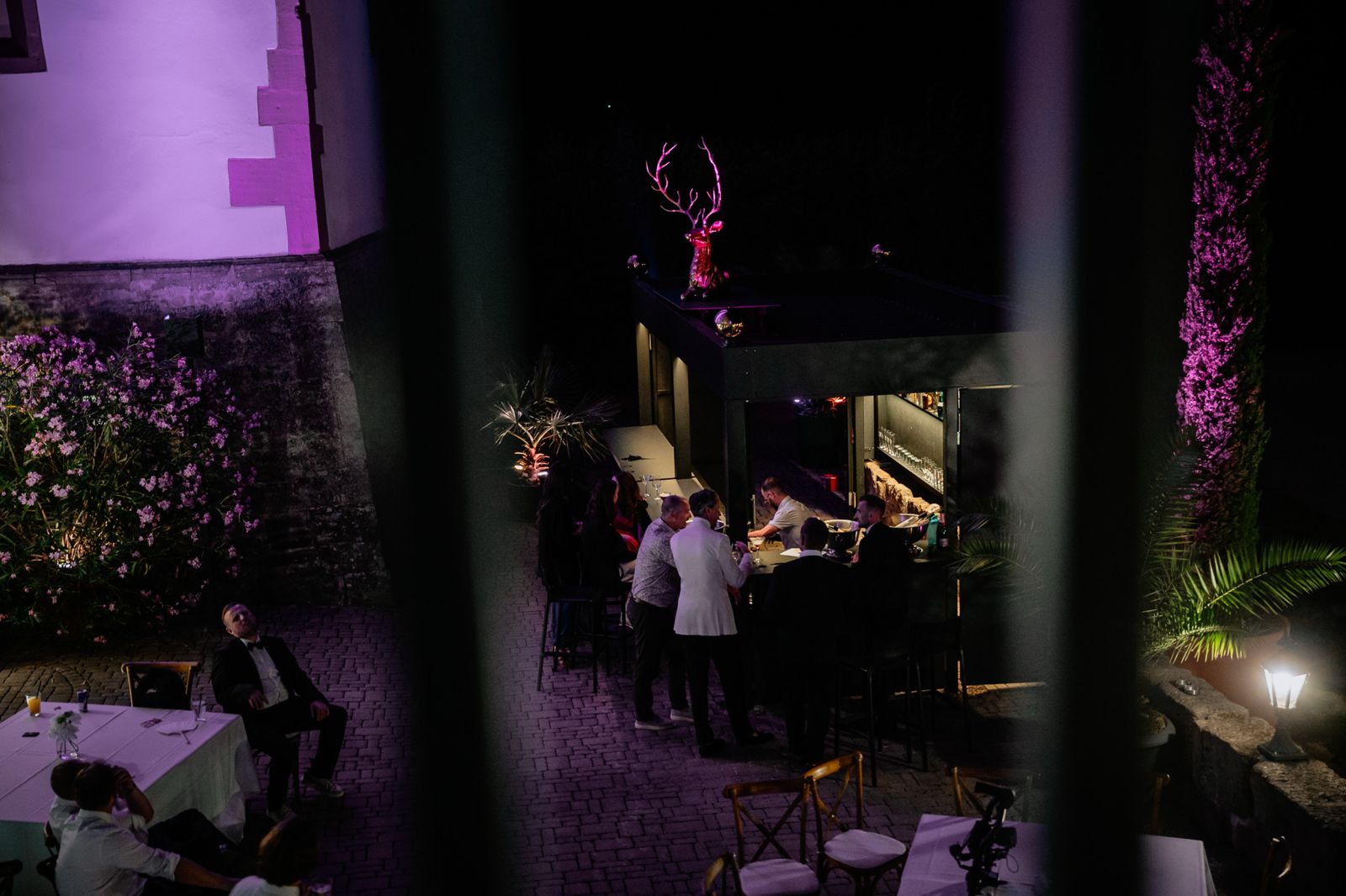 Barkeeper shakt einen Cocktail für zwei Gäste im Smoking