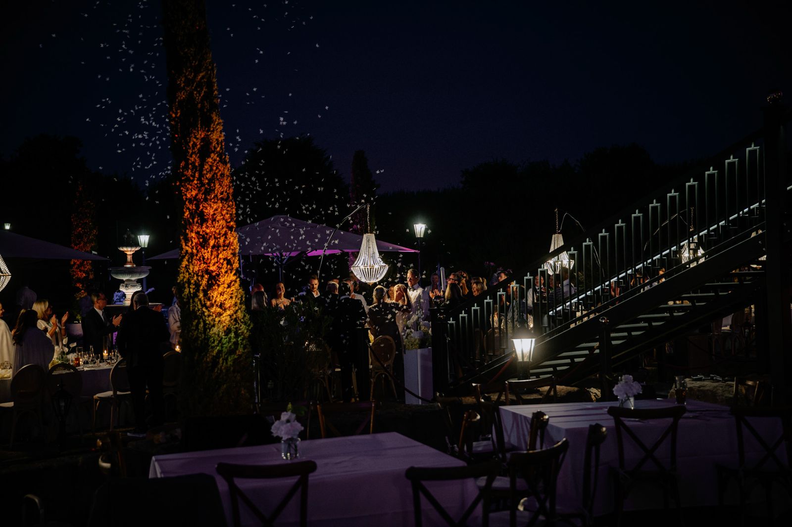 Blick von oben auf die beleuchtete Outdoor-Cocktailbar mit Gästen in der blauen Abendstunde