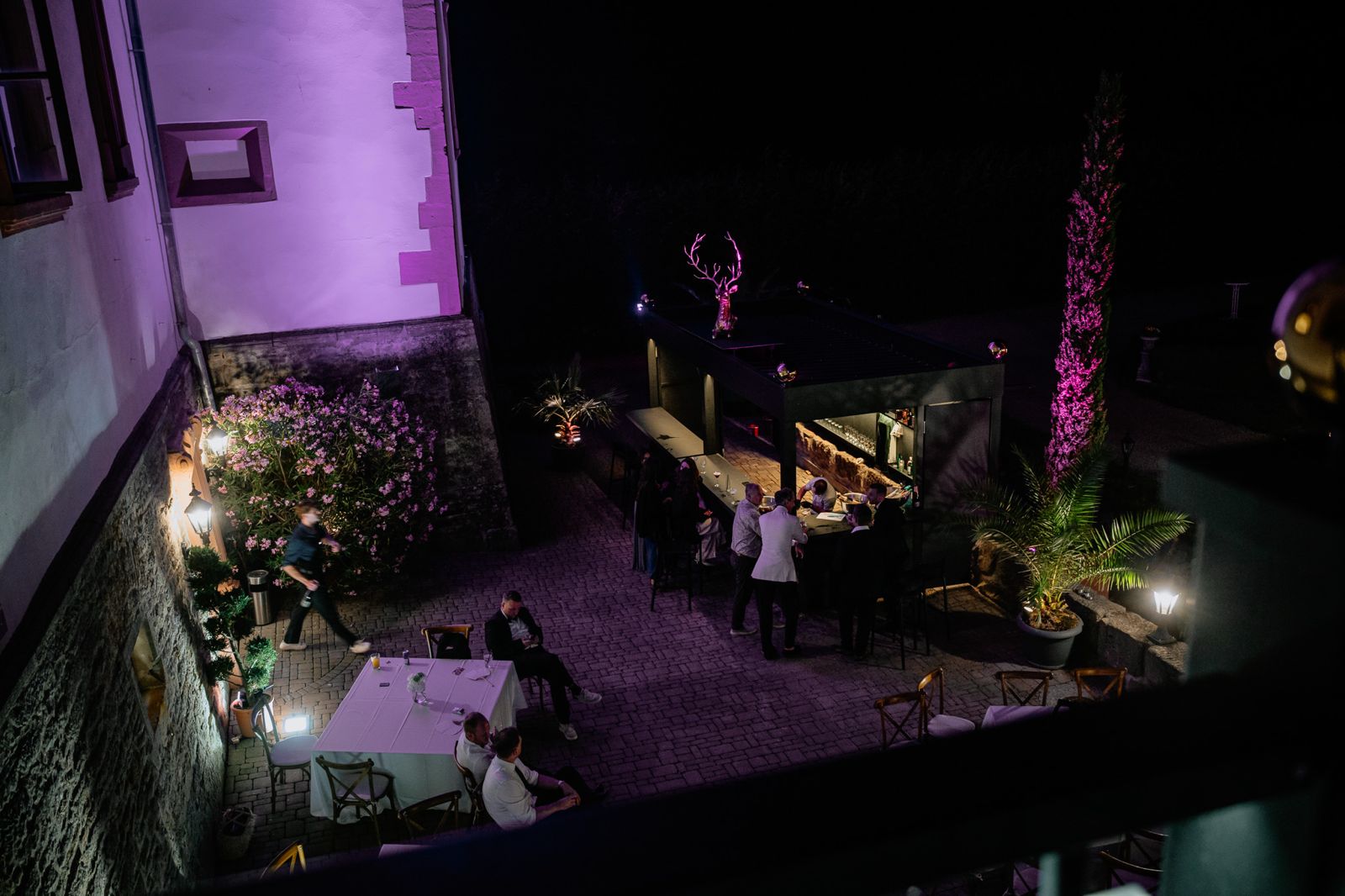 Gäste an der Cocktailbar im nächtlichen Schlosshof