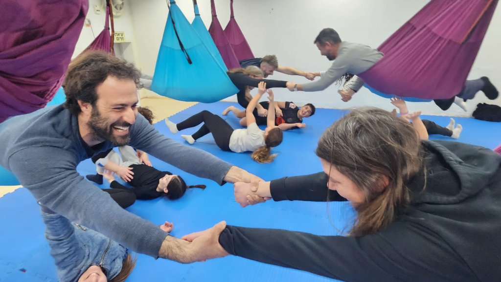 משתתפים מתחברים ונתמכים בתרגול יוגה ערסלים מעצים בסטודיו