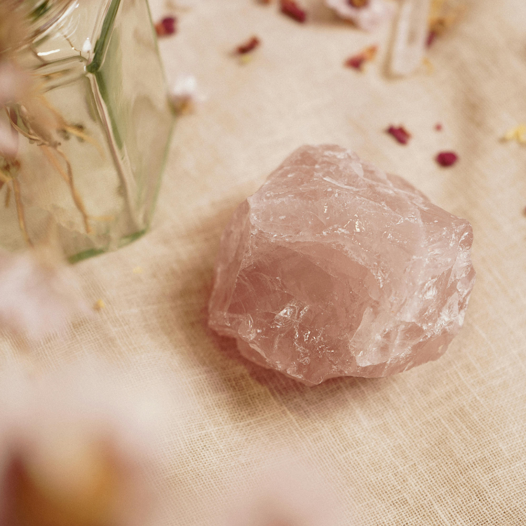 Rose quartz crystal on linen with dried rose petals