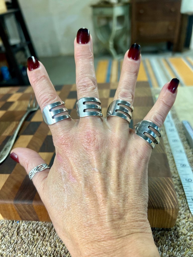 Hand wearing silverware rings