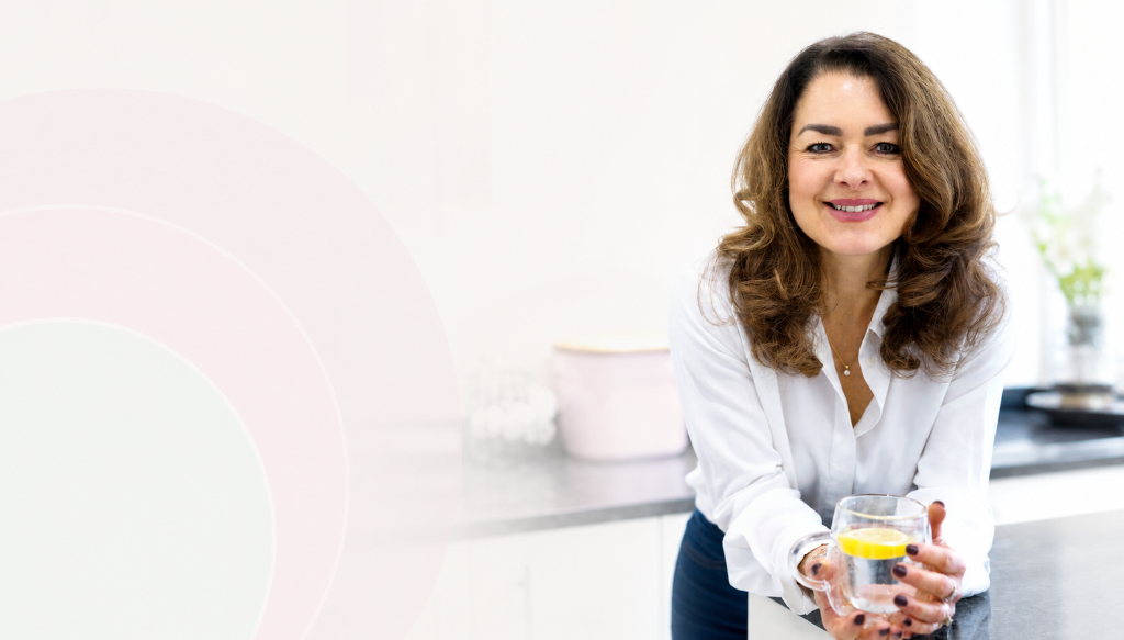 Lucy Childerley leaning on a kitchen counter with a glass of lemon water