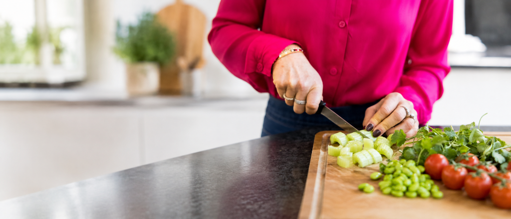 Lucy chopping fresh celery and vegetables on a wooden board