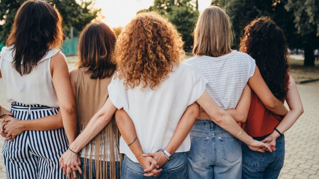 Women supporting each other, linked arm in arm at golden hour