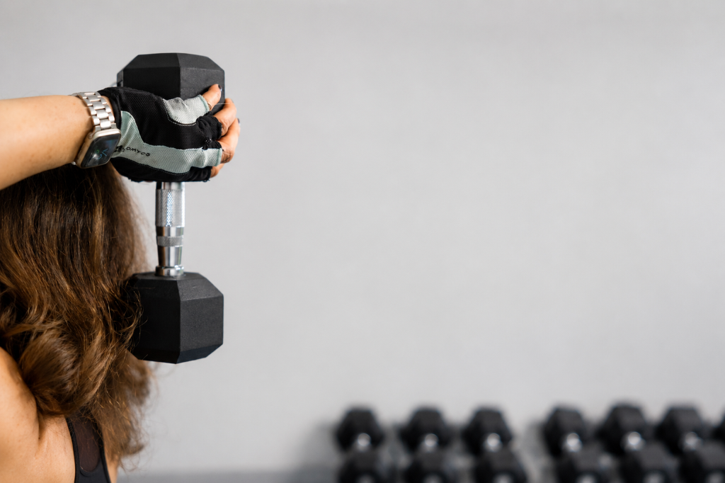 Lucy Childerley holding a dumbbell behind her head in the gym